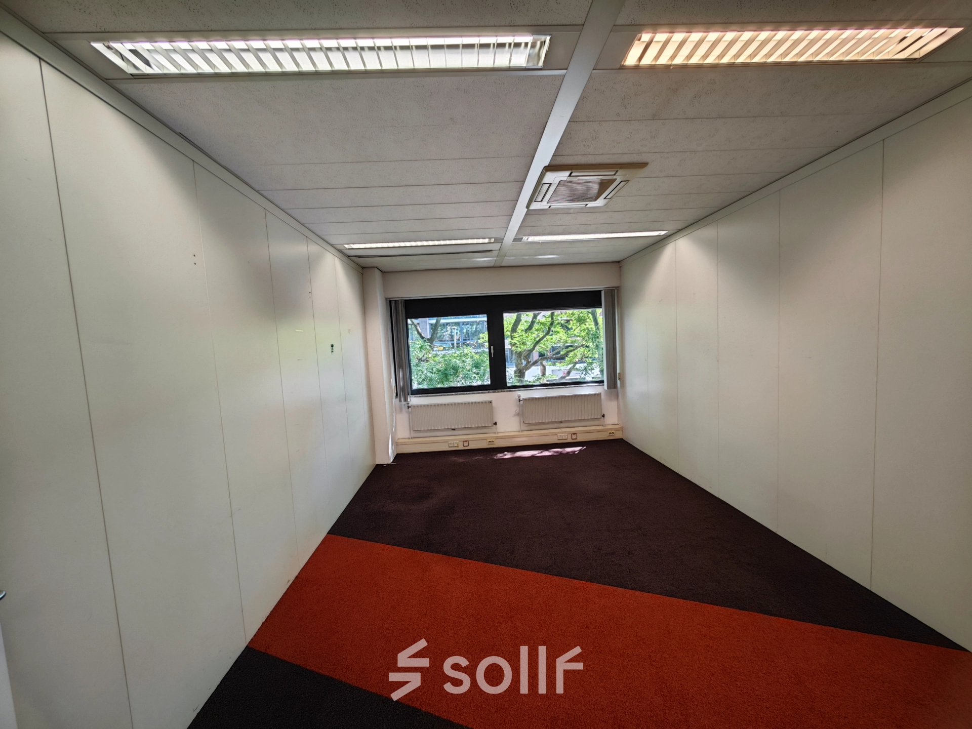 Leeg, goed verlichte kantoorruimte huren in kantoorpand op Bernadottelaan 13, Utrecht Kanaleneiland, met kleurrijke vloerbedekking en een groot raam voor natuurlijk licht.