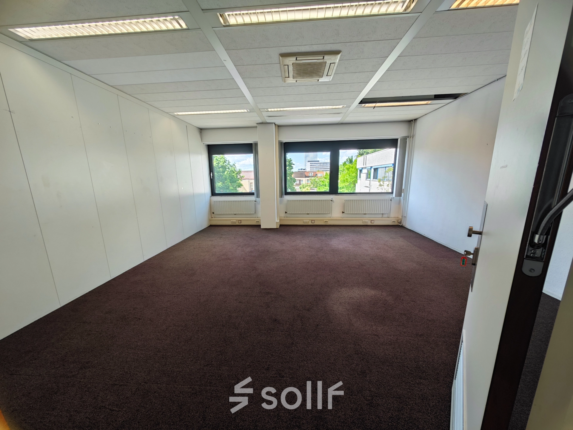 Een lege kantoorruimte op Bernadottelaan 13 in Utrecht Kanaleneiland, geschikt voor huur. Het pand heeft grote ramen die zorgen voor veel daglicht en een warme tapijtvloer.