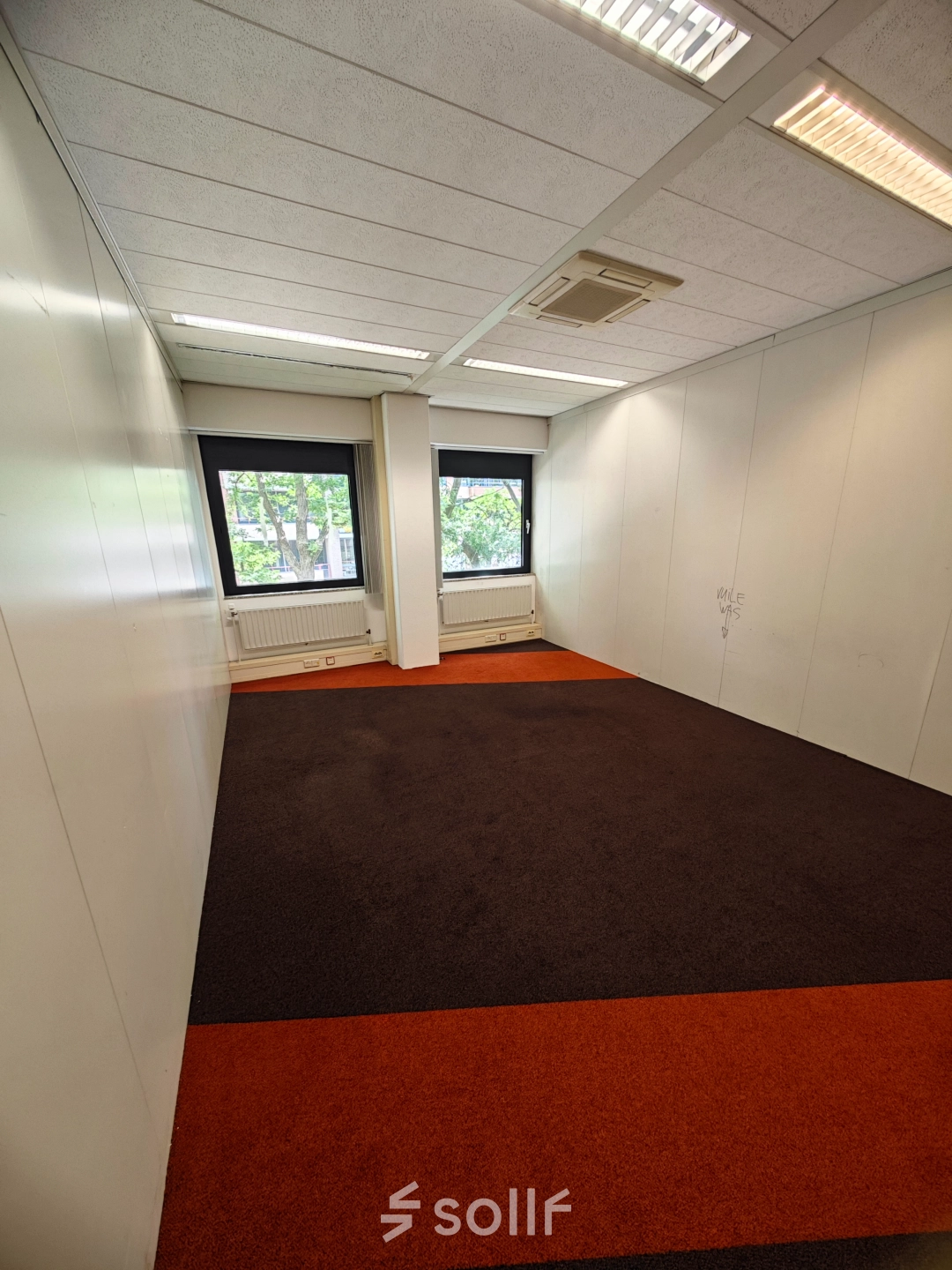 Lege kantoorruimte in Utrecht Kanaleneiland met tapijt, witte wanden en ramen die daglicht binnenlaten. Ideaal voor kantoren en verhuur aan bedrijven.