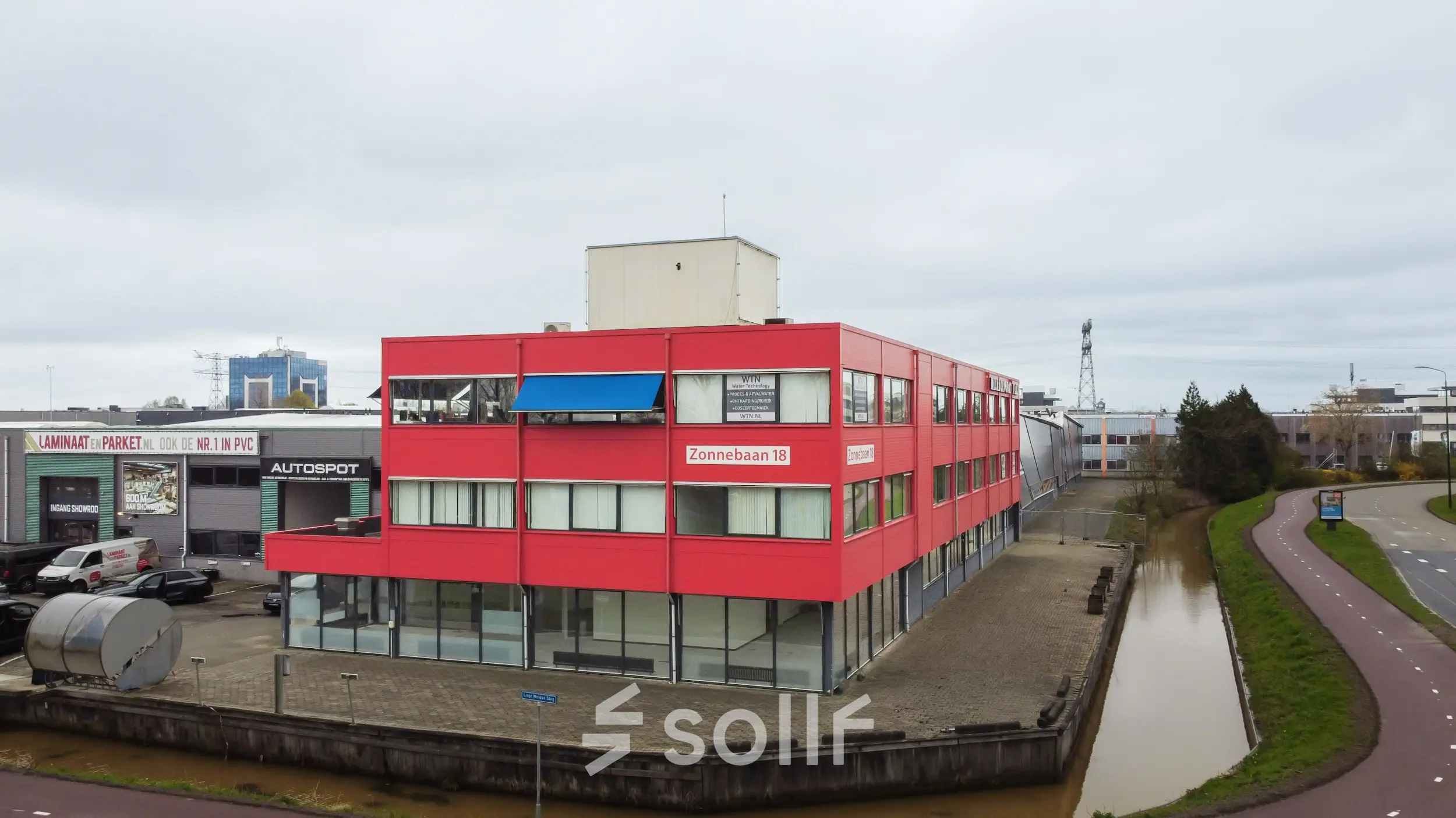 Rood kantoorpand aan Zonnebaan 18 in Utrecht Lage Weide met meerdere verdiepingen en grote ramen, ideaal voor bedrijven die kantoorruimte willen huren of kantoren willen verkennen in dit bedrijventerrein.