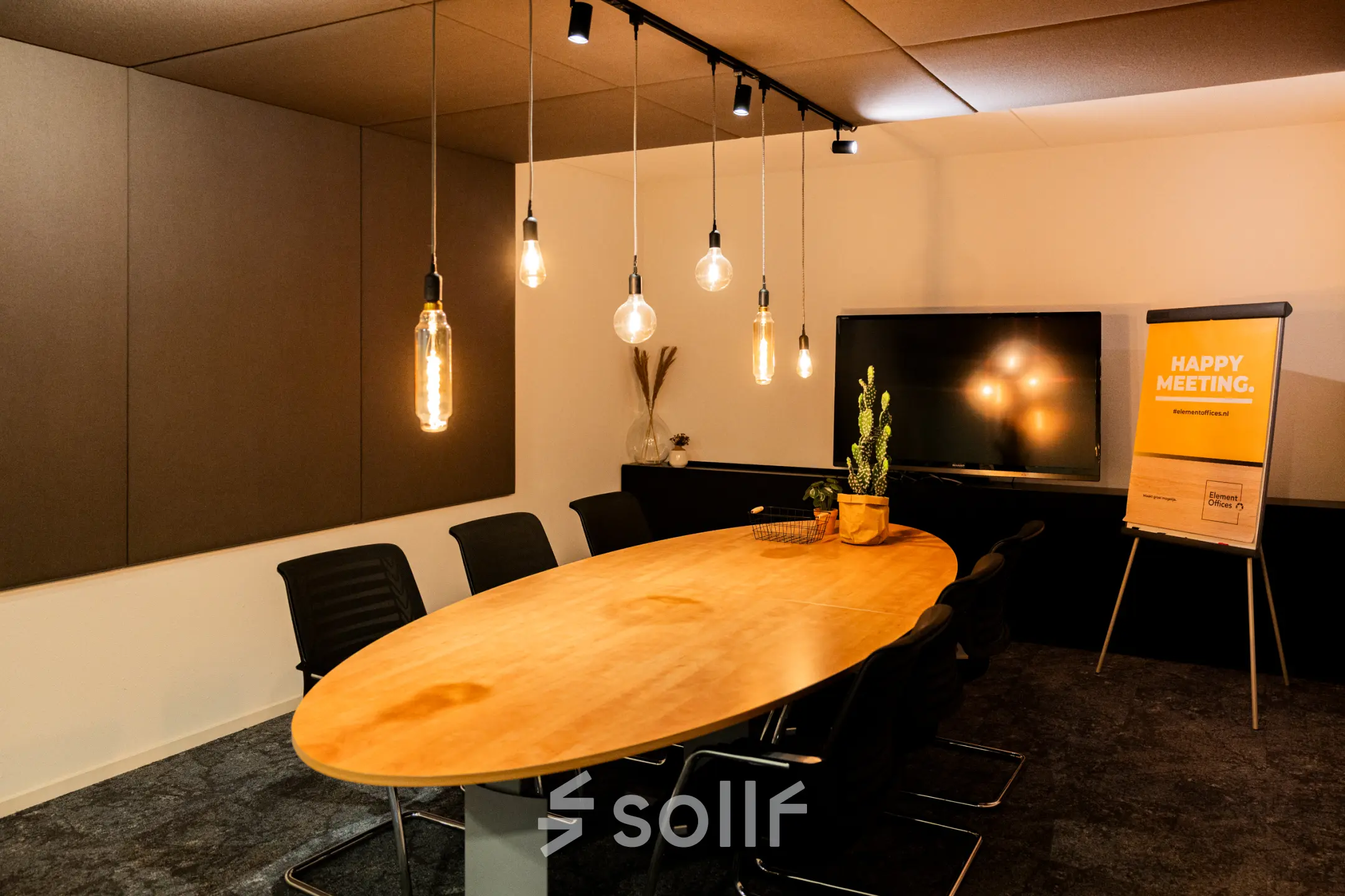 Vergaderruimte met een lange houten tafel, zwarte stoelen en sfeerverlichting, in een kantoorpand op Middenburcht 136, Utrecht Leidsche Rijn.