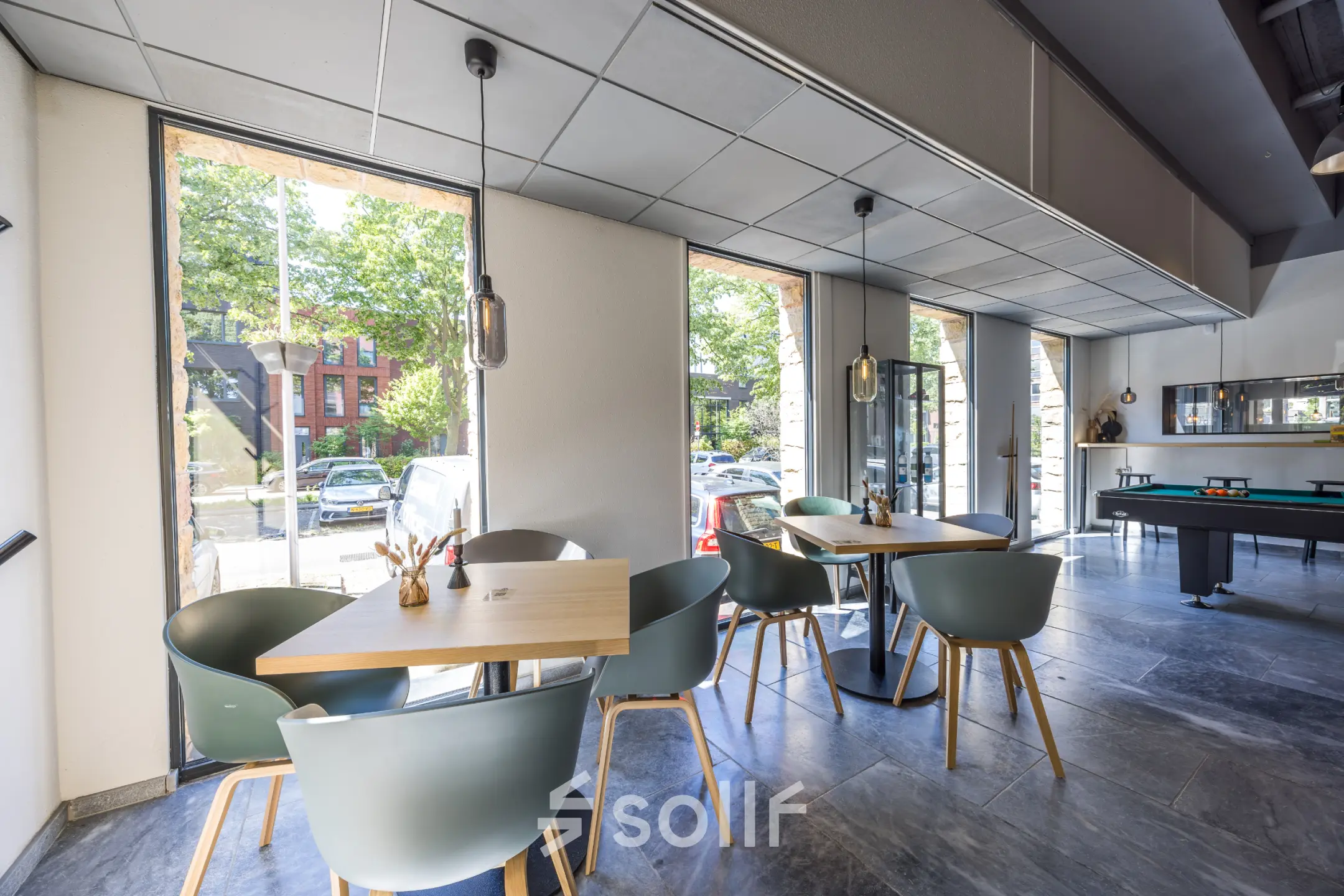 Lichte en moderne kantoorruimte aan de Goeman Borgesiuslaan 77 in Utrecht Noord, met tafels en stoelen nabij grote ramen. Ideaal voor werk of overleg. Gezellige huurkantooromgeving.