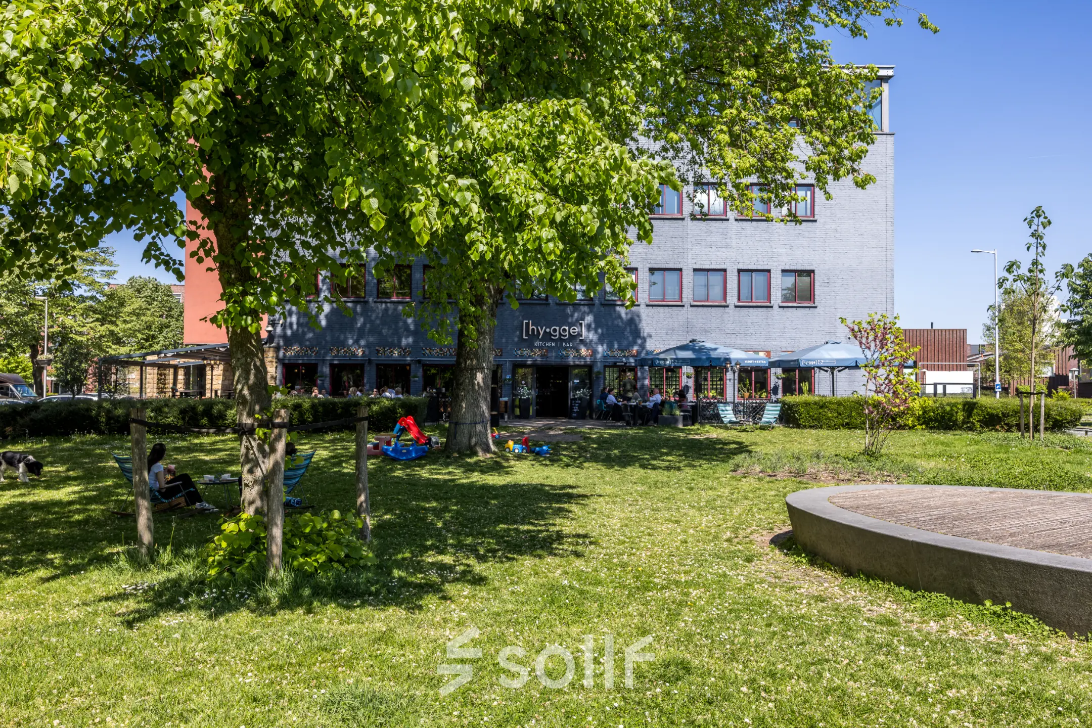 Buitenkant van het kantoorpand aan de Goeman Borgesiuslaan 77 in Utrecht Noord, met een tuin en enkele mensen die buiten werken.