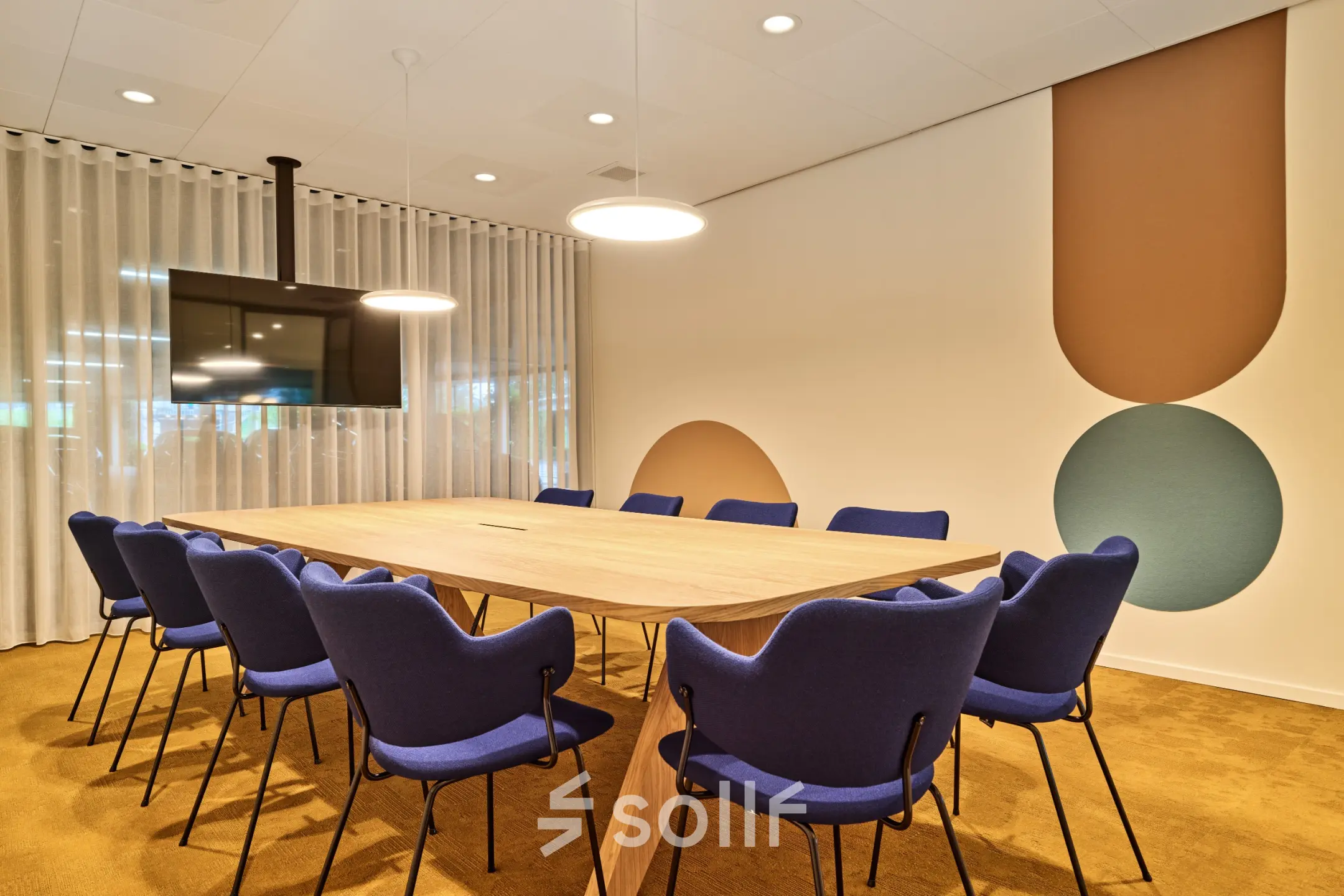 Vergaderruimte in kantoorpand te Utrecht Papendorp met een lange houten tafel omringd door blauwe stoelen en een tv-scherm aan de muur. Gelegen op Van Deventerlaan 30-40. Ideaal voor kantoorruimte huren.