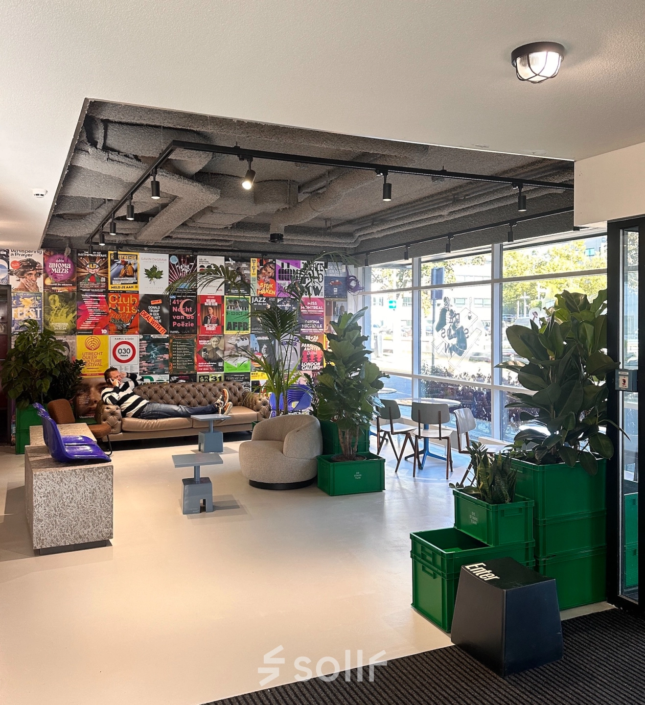 Moderne ontvangstruimte in een kantoorpand met kleurrijke muurposters, planten en comfortabele zitgelegenheid op Daltonlaan 200, Utrecht Rijnsweerd. Ideaal voor kantoorruimte huren.