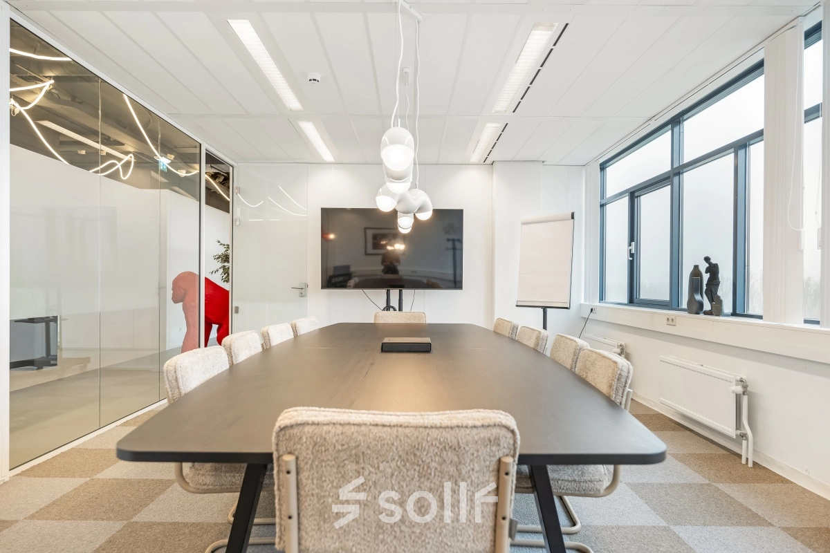 Vergaderruimte in kantoorpand op Daltonlaan 200, Utrecht Rijnsweerd met lange tafel, stoelen en groot scherm. Ideaal voor kantoorruimte huren.