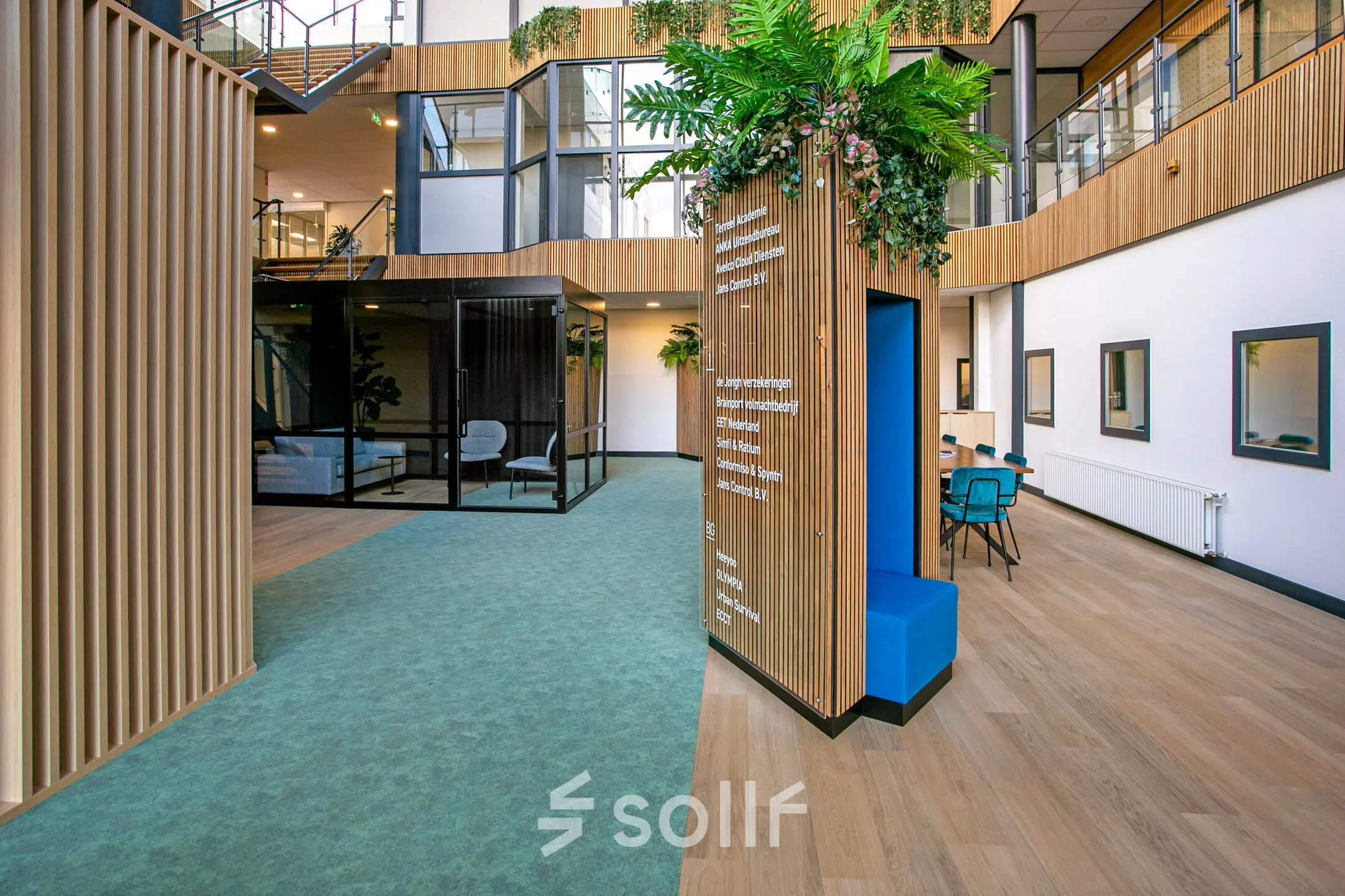Interieur van modern kantoorpand op De Run 4312, Veldhoven, met kleurrijke muren, groen tapijt en een rustige zithoek waar je kantoorruimte kunt huren.