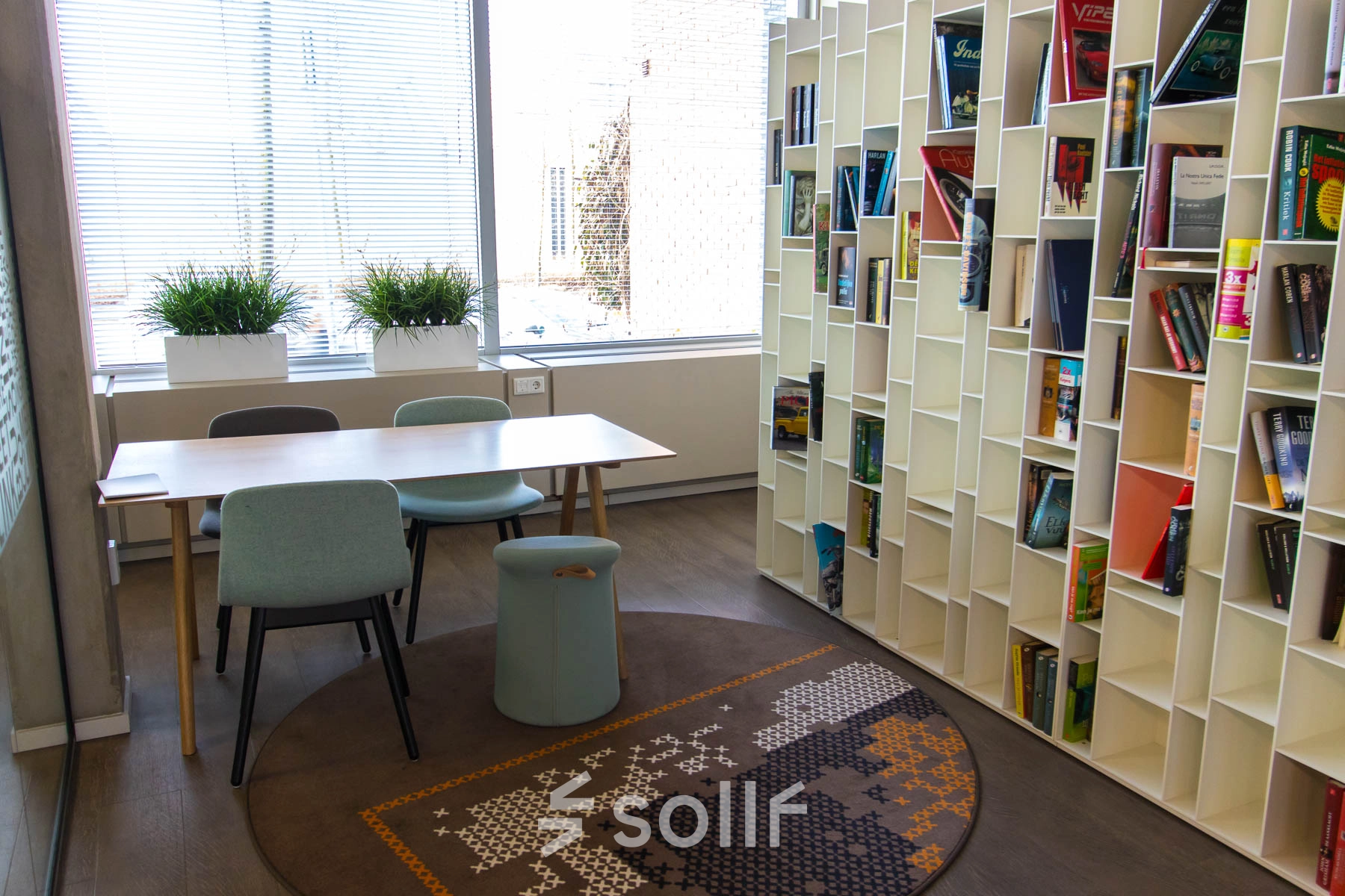 Moderne kantoorruimte op Kaldenkerkerweg 20 in Venlo met grote boekenwand, diverse stoelen en veel daglicht. Ideaal voor wie kantoorruimte wil huren voor creatieve brainstormsessies of als gezellige werkplek.
