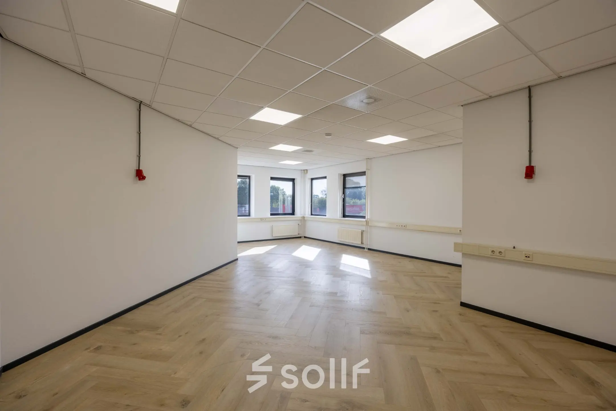 Lichte en open kantoorruimte met houten vloer en uitzicht op het Keizersveld, geschikt voor diverse werkopstellingen.