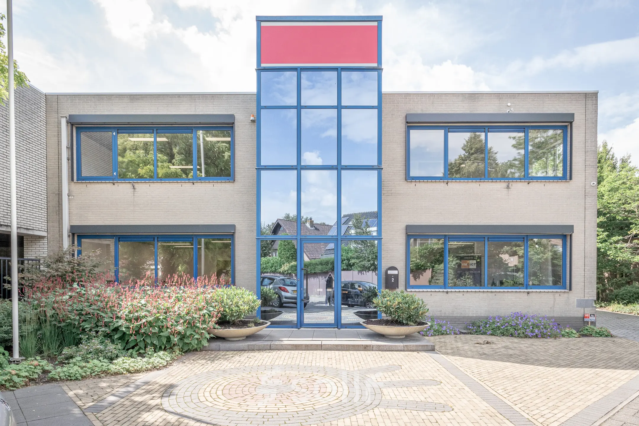 Kantoorpand op Molenweer 2 in Wateringen met moderne gevel en grote ramen, omgeven door groen. Ideaal om kantoorruimte te huren.