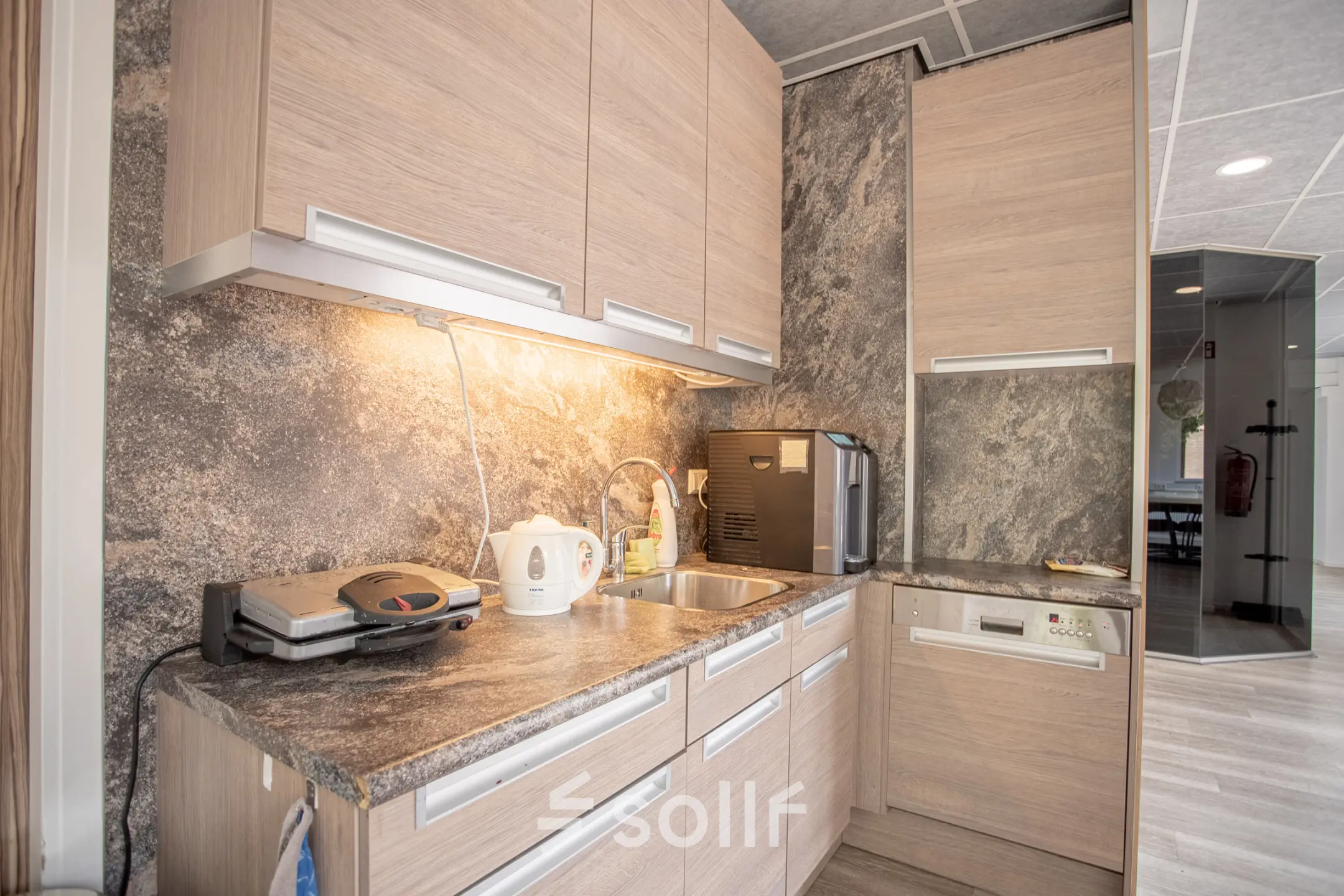 Kantoorruimte huren op Molenweer 2 in Wateringen met een compacte pantry met hout-afgewerkte kasten, inbouwapparatuur en graniet-look werkblad, ideaal voor korte pauzes. Voldoende ruimte voor het bereiden van koffie en snacks.