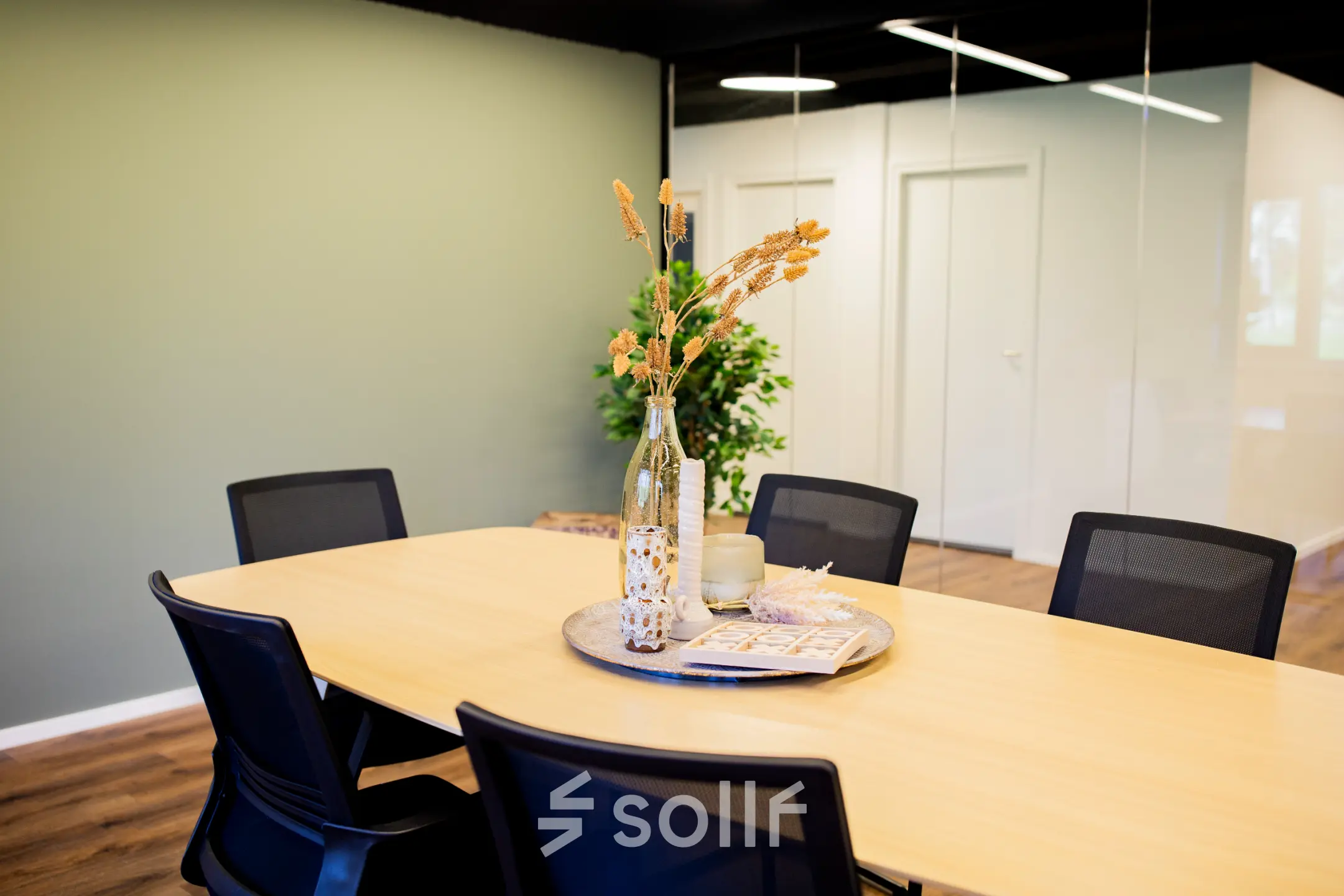 Kantoorruimte huren op Pelmolenlaan 16 in Woerden met een moderne vergadertafel, zes stoelen en decoratieve planten. Deze kantoorruimte is geschikt voor vergaderingen of bijeenkomsten.