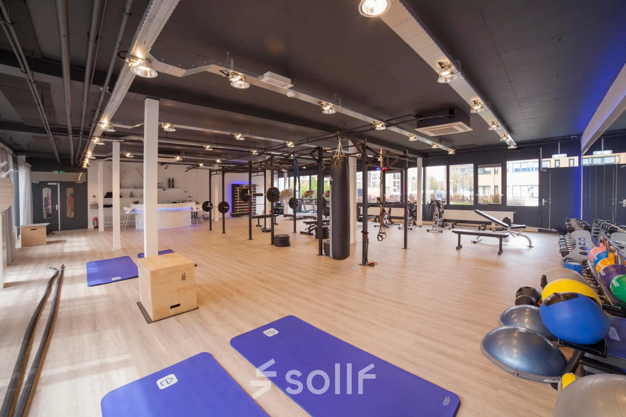 Ruime en modern ingerichte kantoorruimte op Pompmolenlaan 26, Woerden, met een open vloerplan, ideaal om kantoorruimte te huren. De ruimte is ingericht met fitnessapparatuur en lichte houten vloeren.