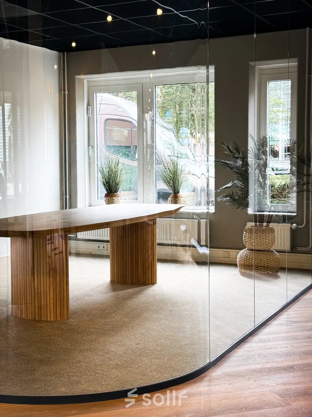 Moderne kantoorruimte in Woerden met houten tafel en glazen wanden. Grote ramen bieden veel licht. Planten zorgen voor een frisse uitstraling, ideaal voor kantoorruimte huren.