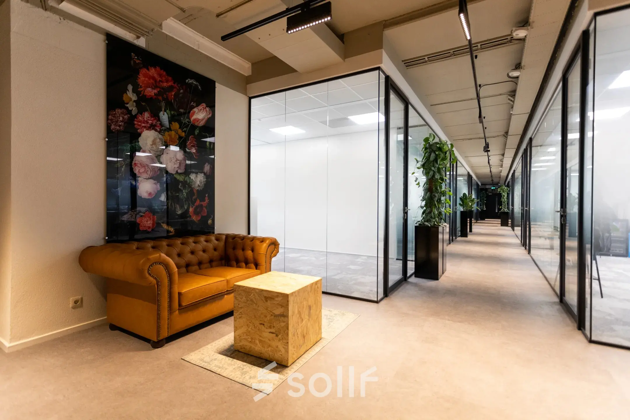 Moderne kantoorgang op Boerhaavelaan 40, Zoetermeer met glazen wanden en een leren bank met kunstwerk. Ideaal voor kantoorruimte huren in een stijlvol pand.