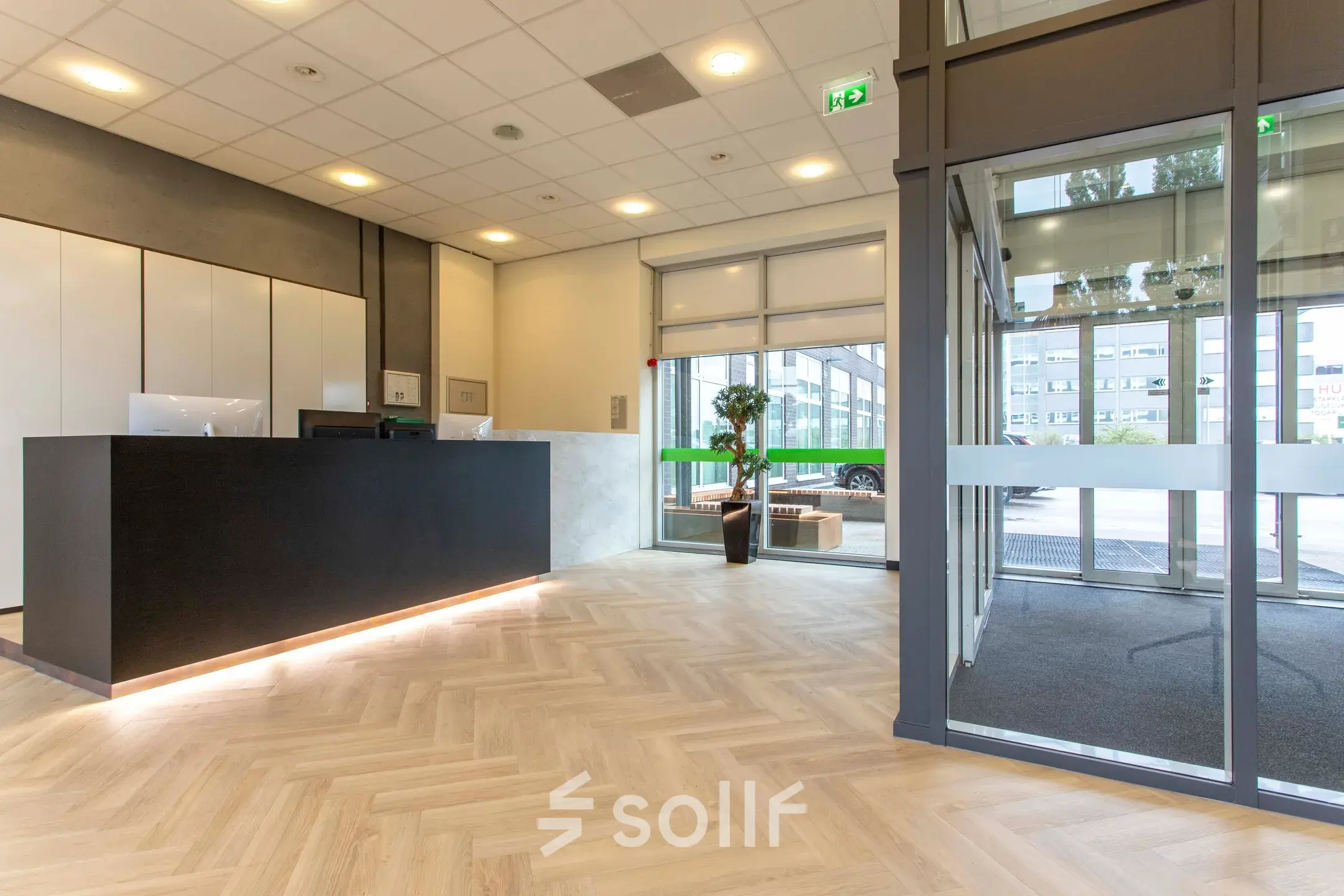 Moderne receptie in kantoorpand aan de Louis Braillelaan 80 in Zoetermeer met donkere balie en verlichte vloer.