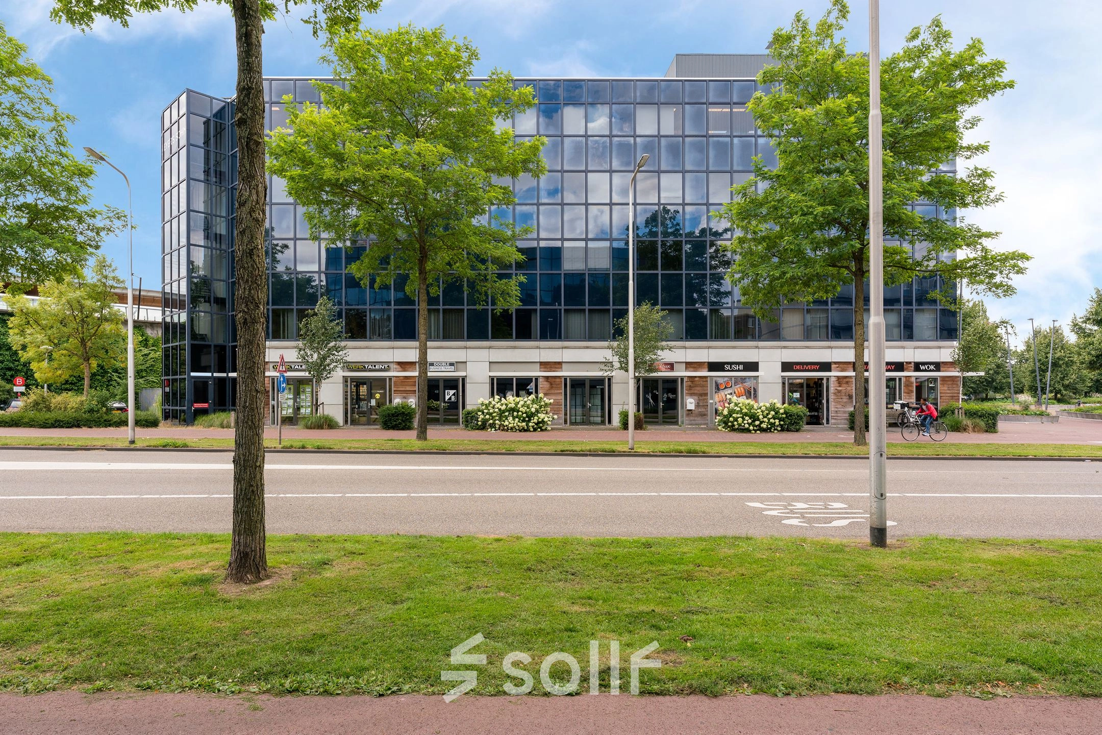 Modern kantoorpand aan Stationsplein 4 in Zwijndrecht met glazen gevel en groene omgeving, ideaal voor kantoorruimte huren.
