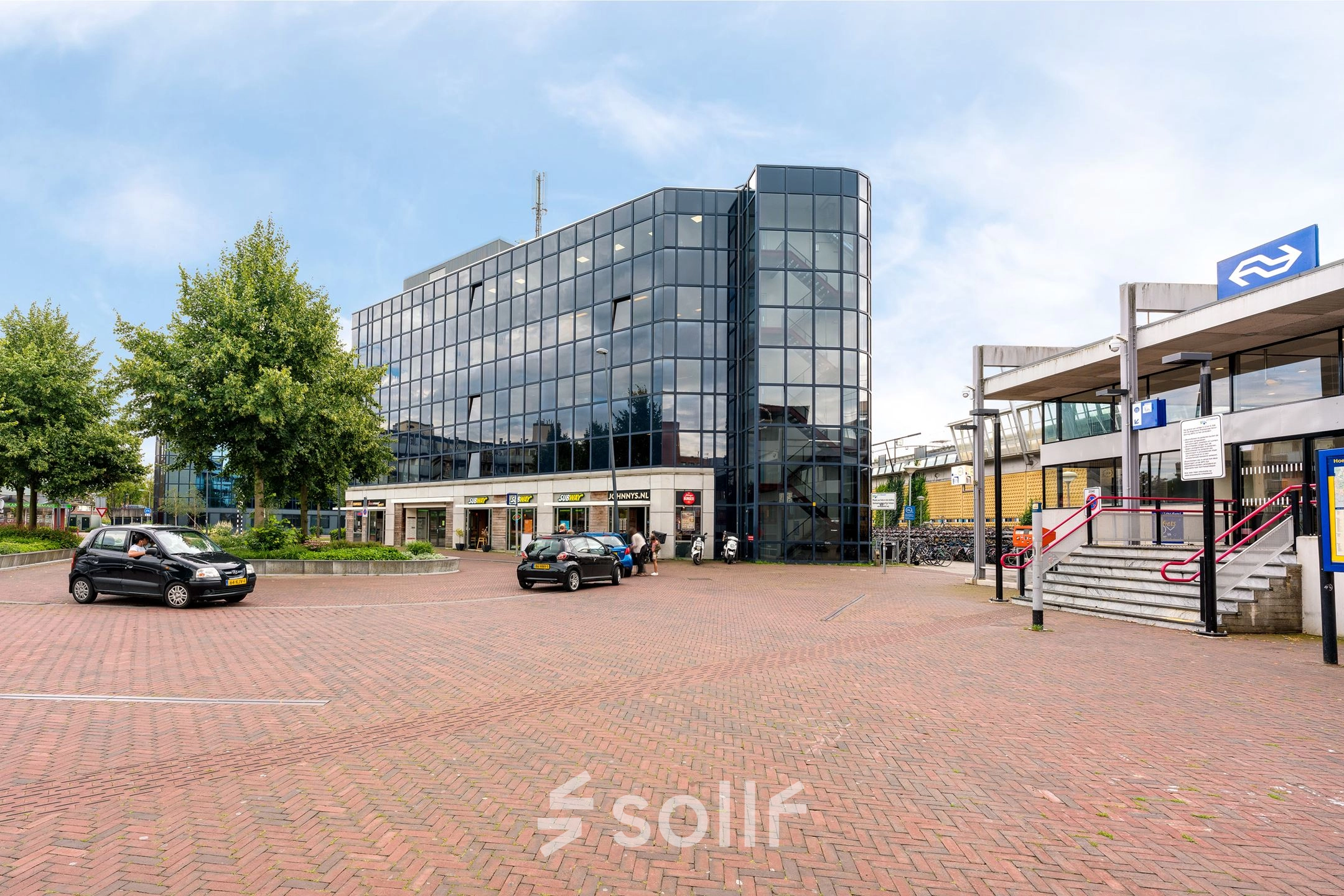 Zakelijk kantoorpand aan het Stationsplein 4 in Zwijndrecht met grote glazen gevel. Het biedt mogelijkheden voor kantoorruimte huren in een moderne omgeving. Buiten zijn geen personen te zien.
