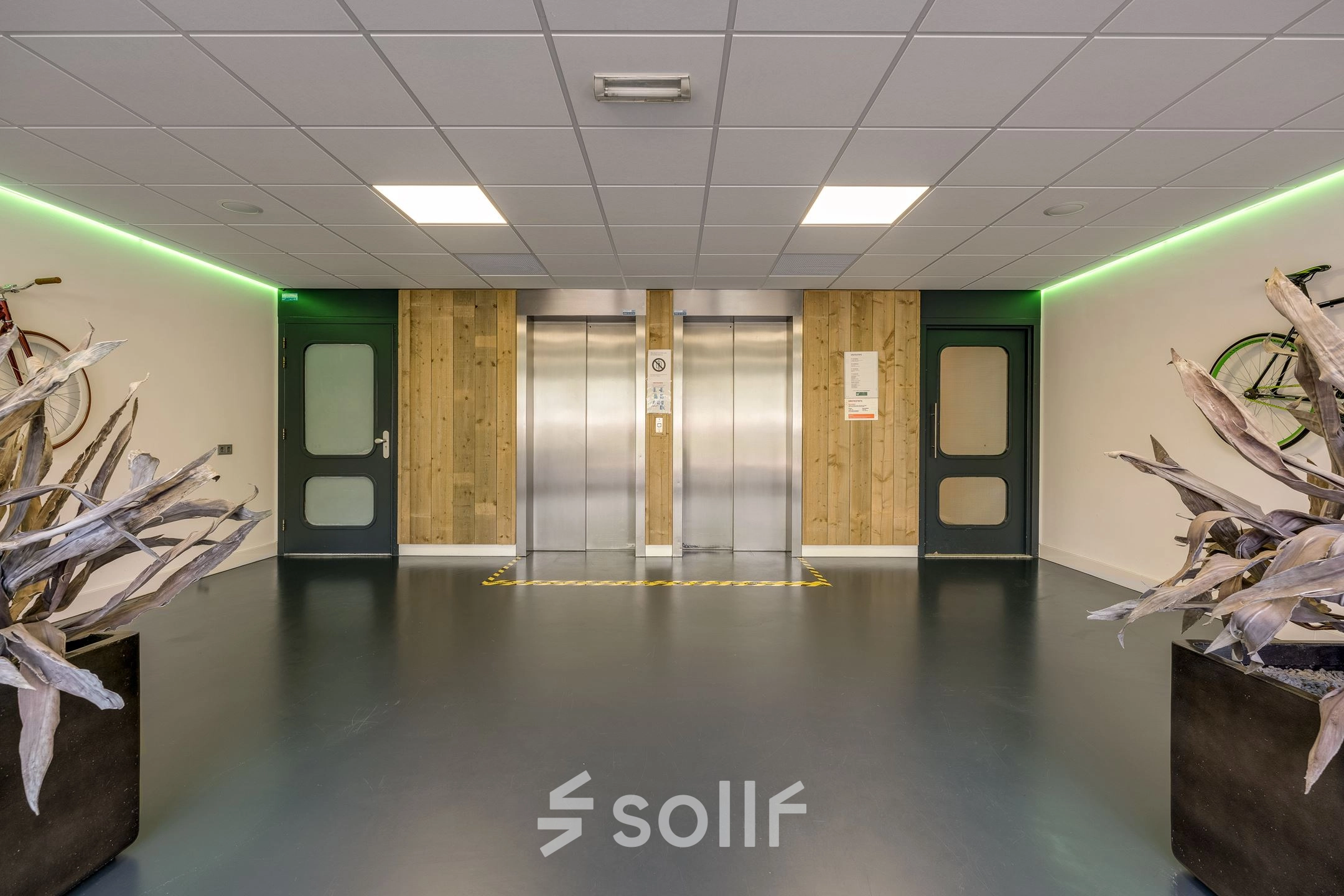 Binnenkant van het kantoorpand op Stationsplein 4 in Zwijndrecht, met een moderne lift en groene verlichting, ideaal voor wie kantoorruimte wil huren.
