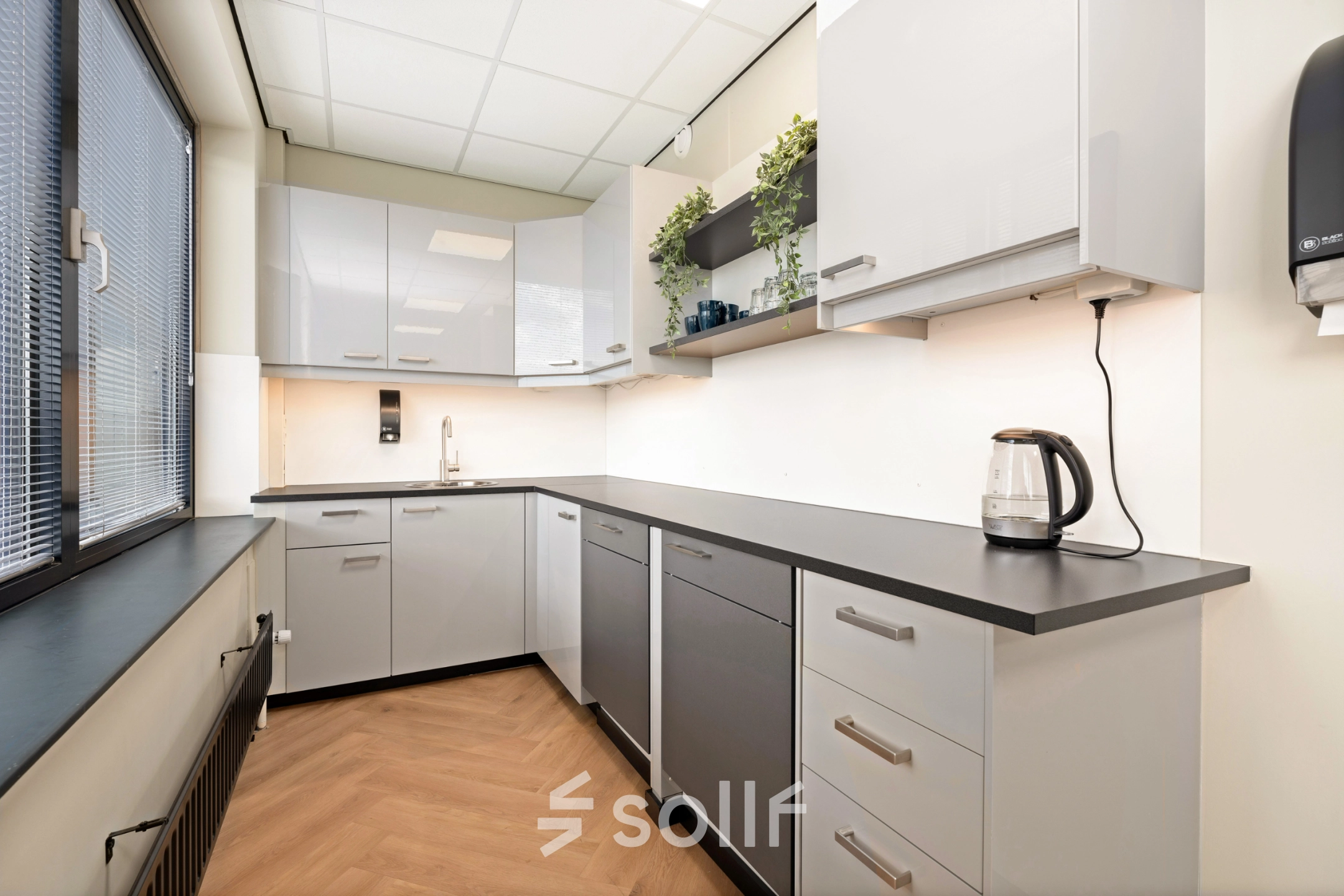 Moderne pantry met strakke kasten en voldoende ruimte, ideaal voor een korte pauze in het kantoorpand op Stationsplein 4, Zwijndrecht. Geschikt voor bedrijven die kantoorruimte huren.