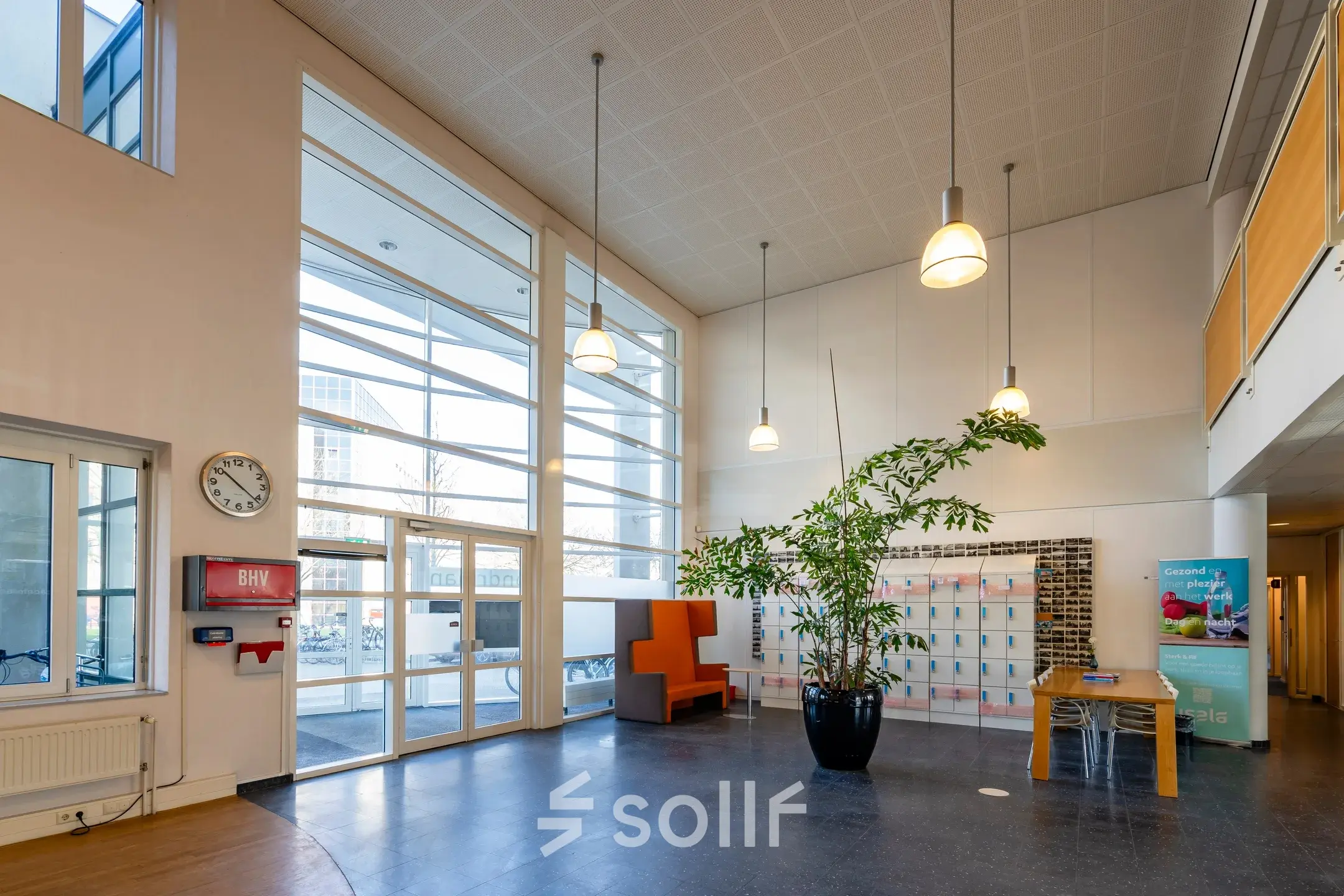 Ruime, lichte entree van een kantoorpand op Dokter van Deenweg 1, Zwolle, met hoge plafonds, veel glas en moderne kunstobjecten. Ideaal voor zakelijke activiteiten en kantoorruimte huren.