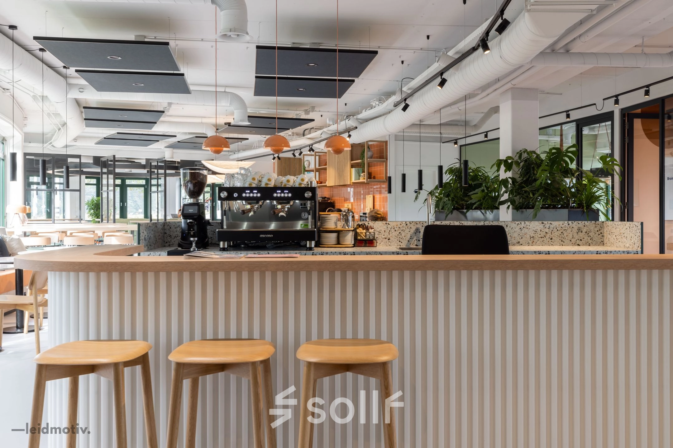 Moderne kantoorruimte huren met open keuken en zitgedeelte op de Hanzelaan 351-361, Zwolle. Gezellige sfeer met houten barkrukken en groene planten. Ideaal voor creatieve kantoren.