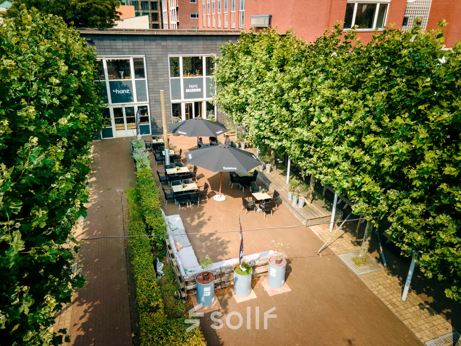 Buitenterras van een kantoorpand op Hanzeplein 11-27 in Zwolle, met zitgelegenheid en parasols. Perfect voor wie kantoorruimte wil huren in een groene omgeving.