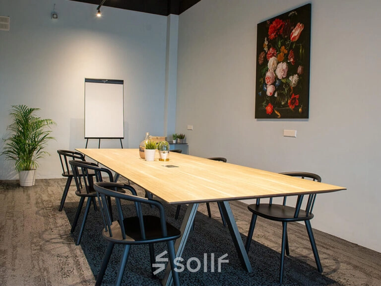 Kantoorruimte huren op Zwartewaterallee 48 in Zwolle met een stijlvolle vergadertafel, moderne stoelen en een wanddecoratie. Planten zorgen voor een frisse uitstraling in deze kantoorruimte.
