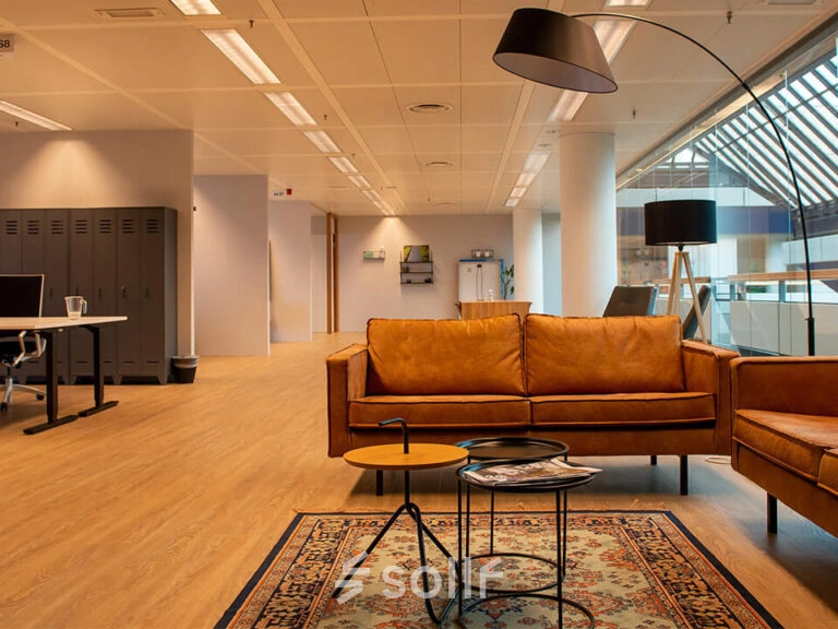 Moderne kantoorruimte op Zwartewaterallee 48 in Zwolle met stijlvolle leren banken, bijzettafels en een vloerkleed, ideaal voor informeel overleg of pauzes tijdens het huren van kantoor.