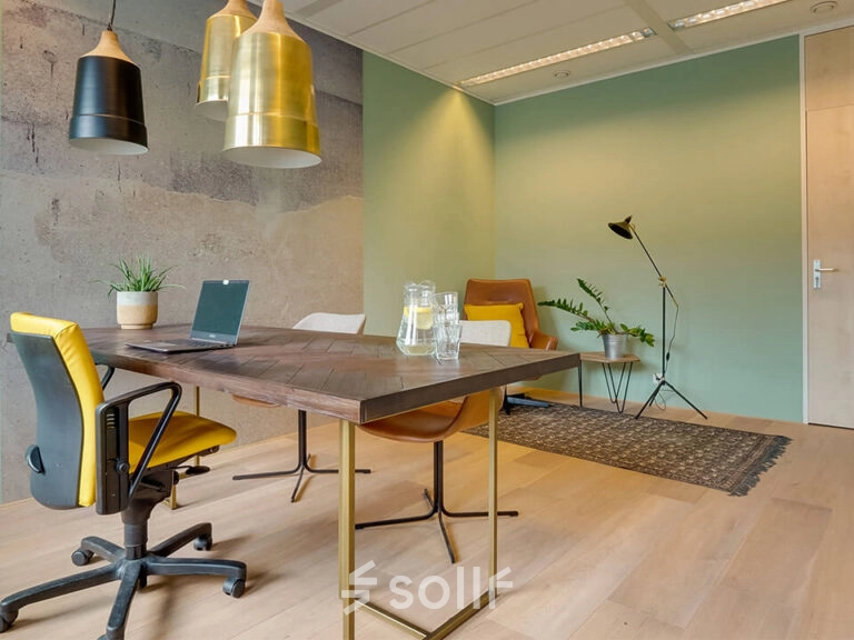 Moderne kantoorruimte huren op Zwartewaterallee 48 in Zwolle met stijlvol meubilair, vergadertafel en stoelen, groene planten en speelse verlichting.