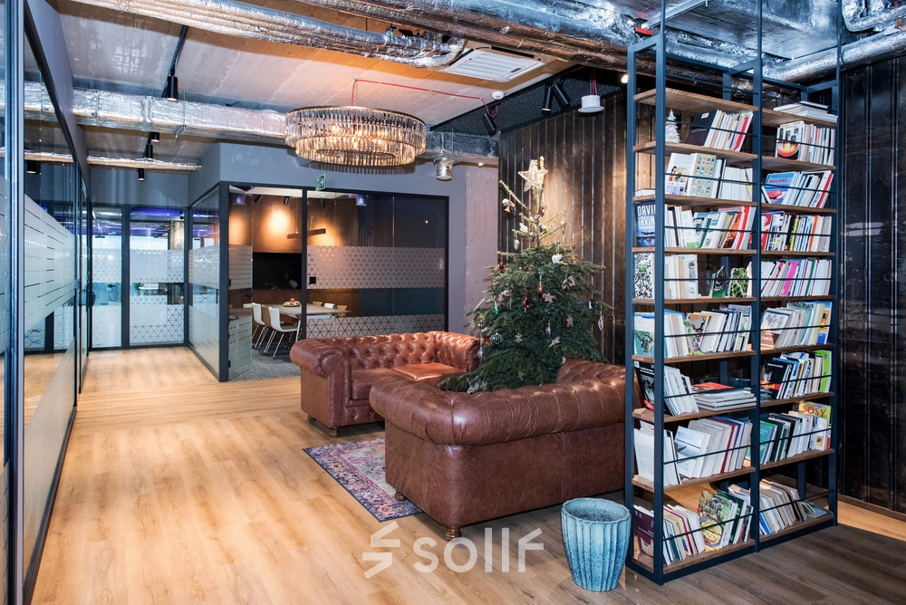 Nowoczesne biuro do wynajęcia na Wadowickiej 7 w Kraków Podgórze, z eleganckimi, umeblowanymi przestrzeniami biurowymi, w tym wygodnym lounge i imponującą biblioteczką.