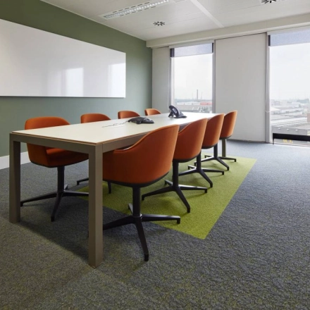 Vergaderzaal met witte muren, een lange tafel en acht oranje stoelen bij Noorderlaan 147, kantoorruimte te huur in Antwerpen Merksem.