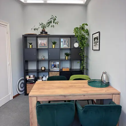 Stijlvol gemeubileerde kantoorruimte te huur op Avenue Palmerston 3 in de Europese Wijk van Brussel, met een houten tafel en groene stoelen, omringd door planten en wanddecoratie.