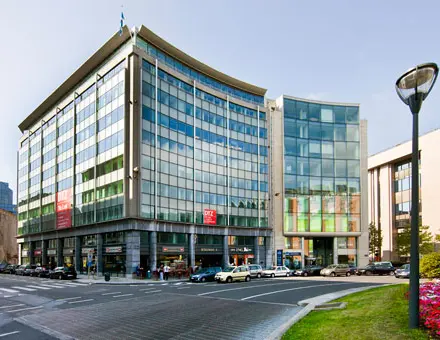 Zakelijk kantoorgebouw op het Robert Schumanplein 2-4 in Brussel Europese Wijk, met moderne glazen gevels en omringd door wegen en auto's, beschikbaar voor kantoor te huur.