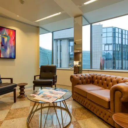 Kantoorruimte te huur op Robert Schumanplein 2-4 in Brussel Europese Wijk, met moderne meubels, kunst aan de muur en uitzicht op omliggende gebouwen.