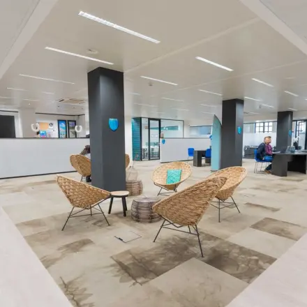Kantoorruimte te huur in Brussel Europese Wijk met moderne werkplekken en informele zitgedeelte. Twee personen voeren zakelijke activiteiten uit aan een lang bureau.