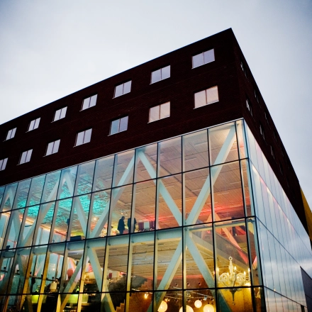 Modern kantoorgebouw met glazen gevel en zicht op kleurrijke binnenverlichting, gelegen op Diamantstraat 8 in Herentals.