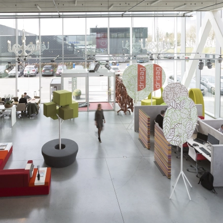 Moderne kantoorruimte te huur in Herentals, met kleurrijk interieur en flexibele werkplekken. Medewerkers bezig aan hun bureau en ontspannen loungehoek. Ruime ramen zorgen voor veel natuurlijk licht.