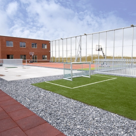 Buitenaanzicht van het gebouw op Diamantstraat 8, Herentals, met sportvelden en open lucht. Kantoorruimte te huur op een strategische locatie.