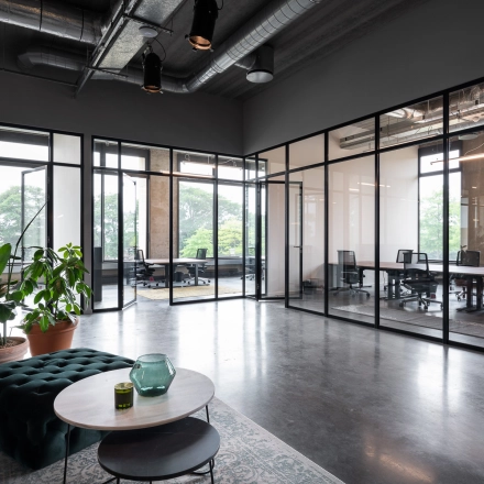 Moderne kantoorruimte te huur op Philipssite 5 in Leuven, met glazen wanden, planten en comfortabele meubels. Ideaal voor bedrijven die kantoorruimte willen huren.