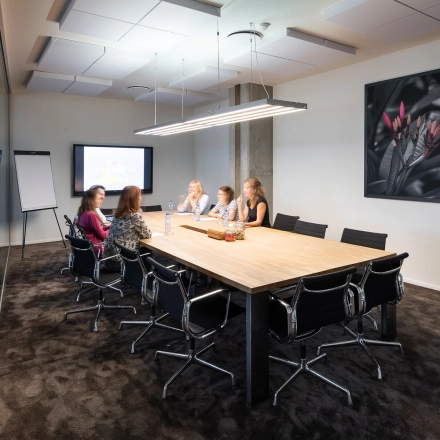 Vergaderruimte in kantoor te huur op Philipssite 5, Leuven, met vijf personen aan een grote tafel, scherm en flip-over in de achtergrond.