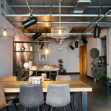 Moderne kantoorruimte te huur op Philipssite 5, Leuven, met stijlvolle verlichting, houten tafel en decoratieve planten, ideaal voor creatieve vergaderingen en samenwerking.