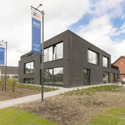Modern zwart gebouw op Olenseweg 375 in Westerlo met ruime vensters, omgeven door groen en gelegen aan een rustige straat. Uitstekende optie voor wie kantoorruimte wil huren.