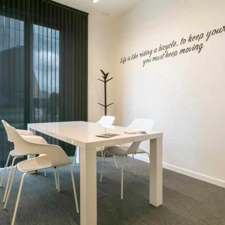 Moderne kantoorruimte te huur in Westerlo met strakke witte tafel en vier stoelen, ideaal voor zakelijke bijeenkomsten.