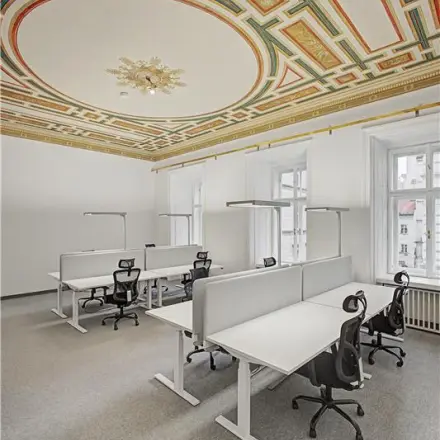 Elegante Bürofläche mieten in 1010 Wien mit dekorativer Decke und modernen Arbeitsplätzen, ideal für Kreativteams.