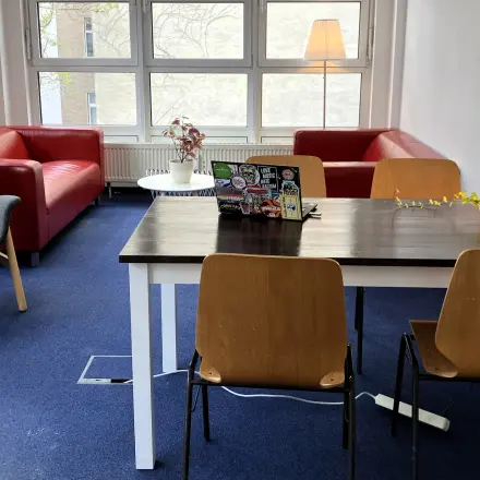 Gemütlicher Büroraum in Berlin Kreuzberg mit Tisch, Stühlen und Sofa für eine entspannte Arbeitsatmosphäre. Bürofläche mieten leicht gemacht.