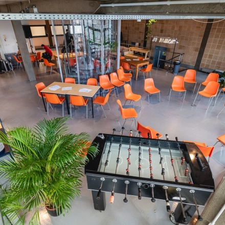 Büroraum in der Rudi-Dutschke-Straße 23, Berlin Kreuzberg, mit orangenen Stühlen, Tischfußballtisch und Pflanzen. Ideal für kreatives Arbeiten und Meetings.