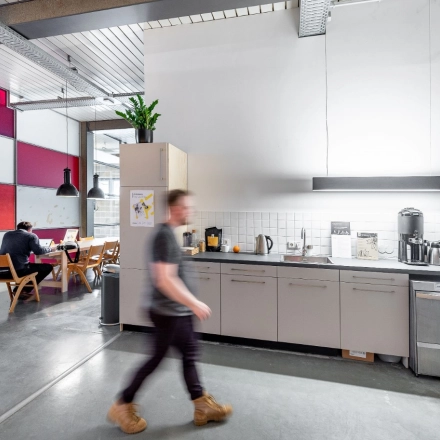 Moderner Büroraum in Berlin Kreuzberg mit funktionaler Küche und Menschen, die arbeiten. Ideal, um Bürofläche oder Büroraum zu mieten.