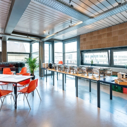 Heller Büroraum mit großen Fenstern in der Rudi-Dutschke-Straße 23, Berlin Kreuzberg, ideal zum Bürofläche mieten mit modernen orangen Stühlen und Tischgestaltung.
