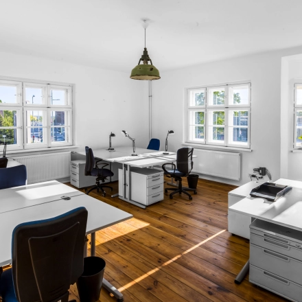 Helles Büro mit Holzboden, mehreren weißen Schreibtischen und Stühlen im Berlin Lichtenberg. Perfekt zum Büro mieten oder Büroraum mieten.